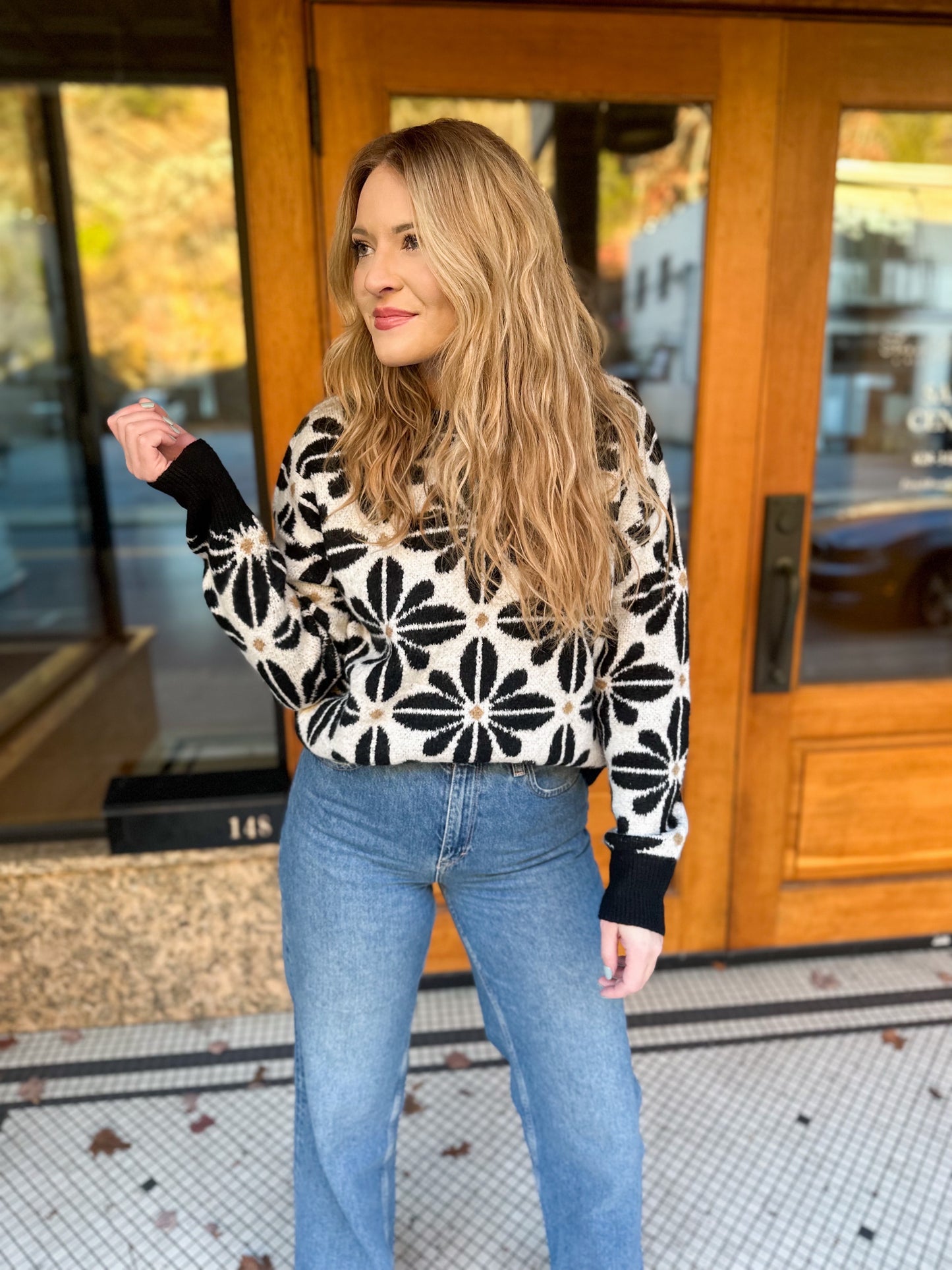 Black and white floral sweater with a slight crop front tucked into a medium wash pair of jeans.